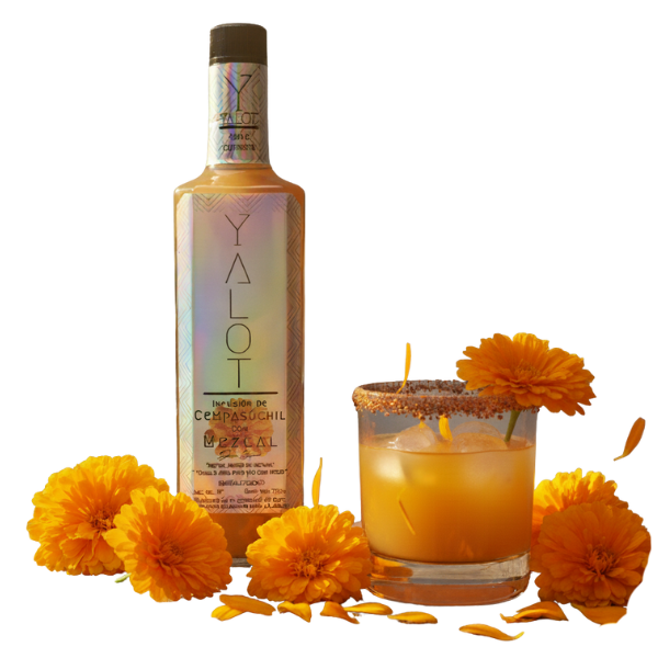 Botella infusión de cempasúchil con mezcal yalot con un vaso servido escarchado y flores de cempasúchil